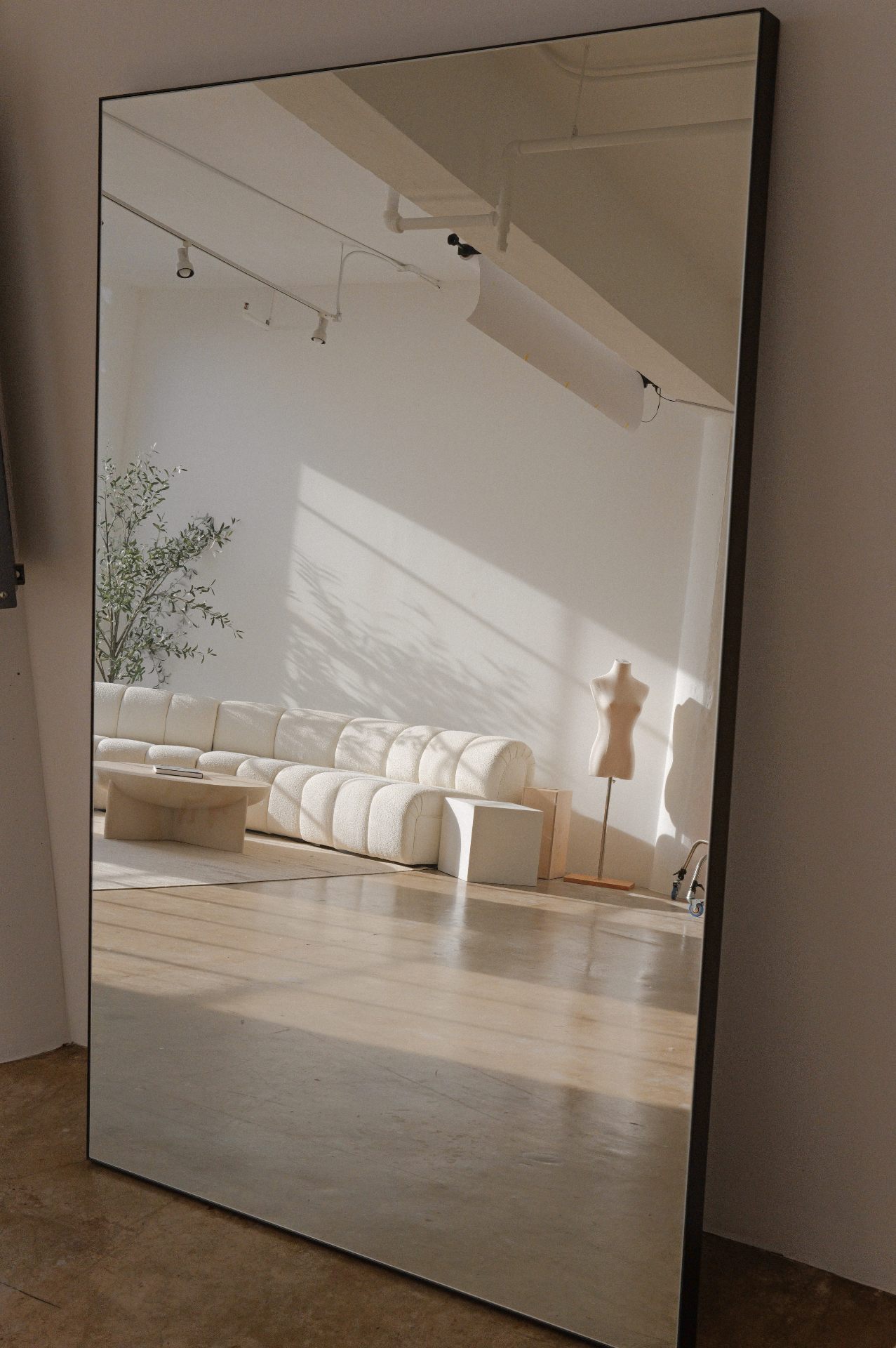 Full-length mirror reflecting the sofa and daylight in Studio 1112